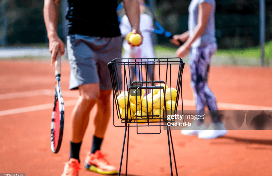 Entrenamiento de tenis con canasto de pelotas